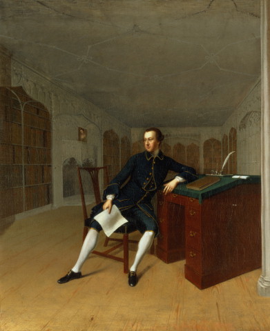 An oil painting of a white man with short dark hair sat on a chair in the middle of a room. His left arm is leaning on a writing slate desk. The desktop is green and the body is red. There is a book, quill and ink pot on the desk and four drawers on the right side of the desk. The man is wearing dark clothes and black shoes with buckles and is holding a piece of paper in his right hand. In the room are book shelves and a fire place.